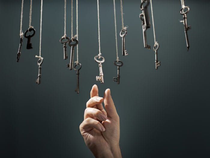 a hand picking a key from a lot of keys hanging from above