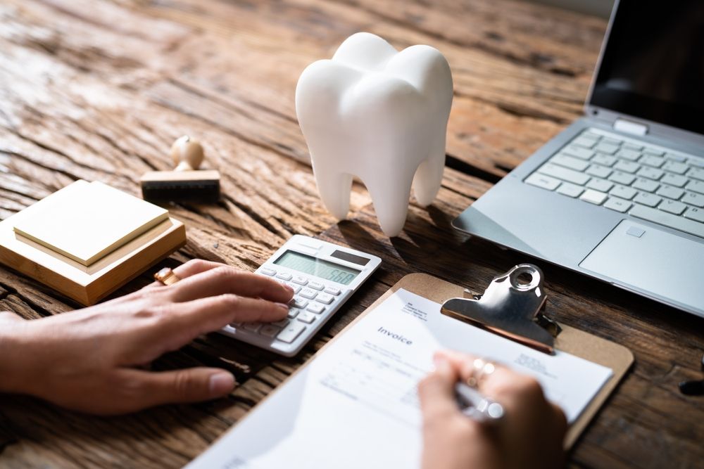 Desk Showing Accounting With Calculator And Paper Next To A Tooth Decorative Item