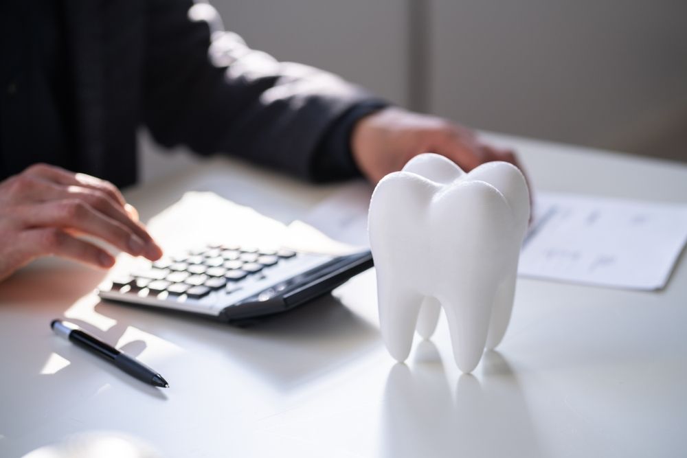 Tooth model in a desk with a view of someone using a calculator